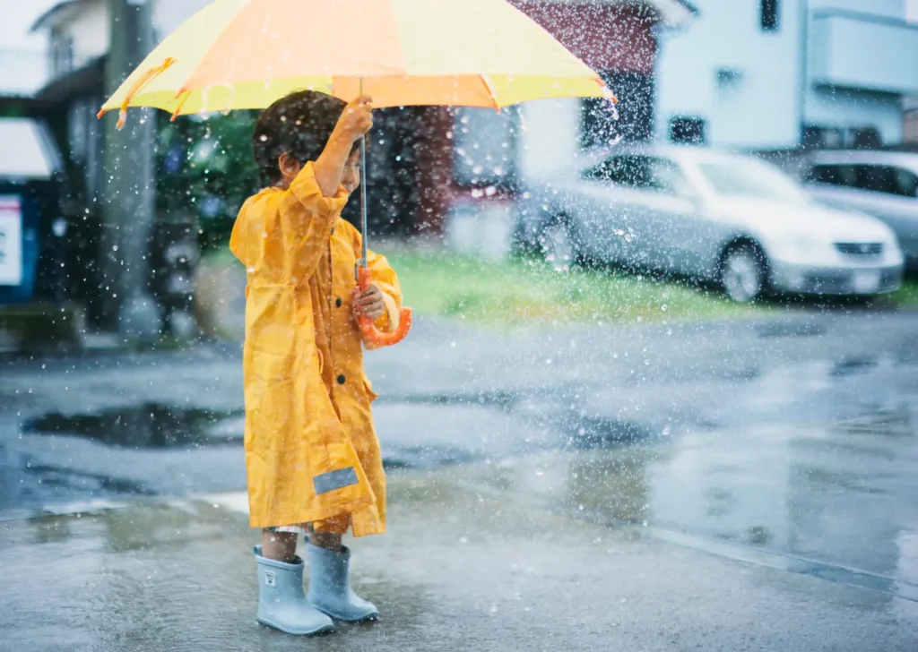 a child holding an umbrella in the rain